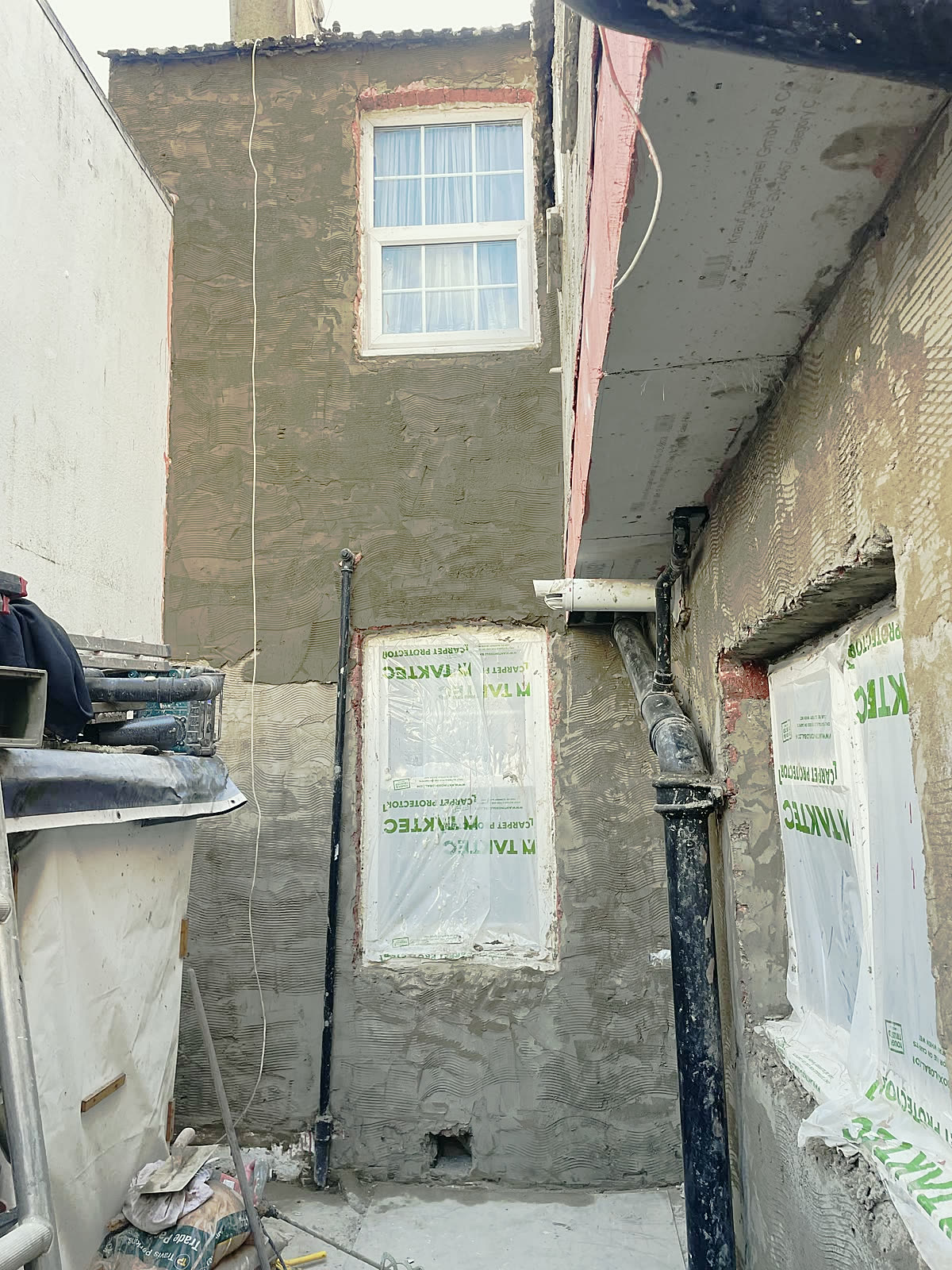 Base coat on a flint and brick wall, windows protected
